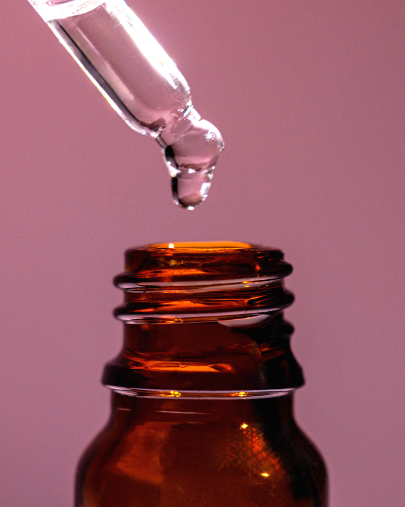 Close-up of Morimoon Luxurious Rose Essential Oil dropper above amber bottle