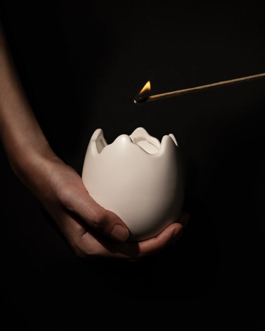 Hands lighting the Ovonique ceramic candle jar – elegant sculptural egg-shaped design