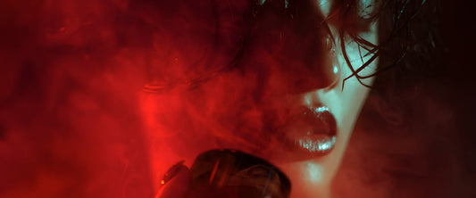 Velvet Ember sample vial against fiery red background, representing smouldering elegance and unforgettable presence.